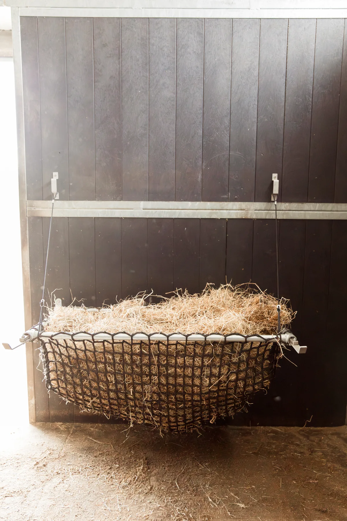 Easy Slowfeeder hooinet, gevuld en opgehangen aan de stalwand