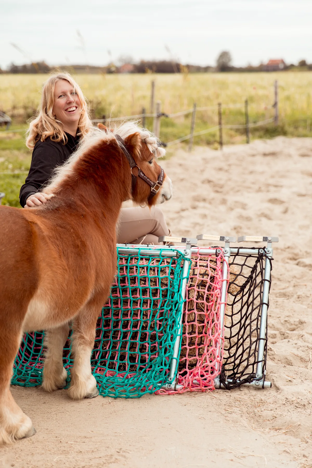Albertine met haar pony naast drie Easy Slowfeeders in verschillende maaswijdtes en kleuren